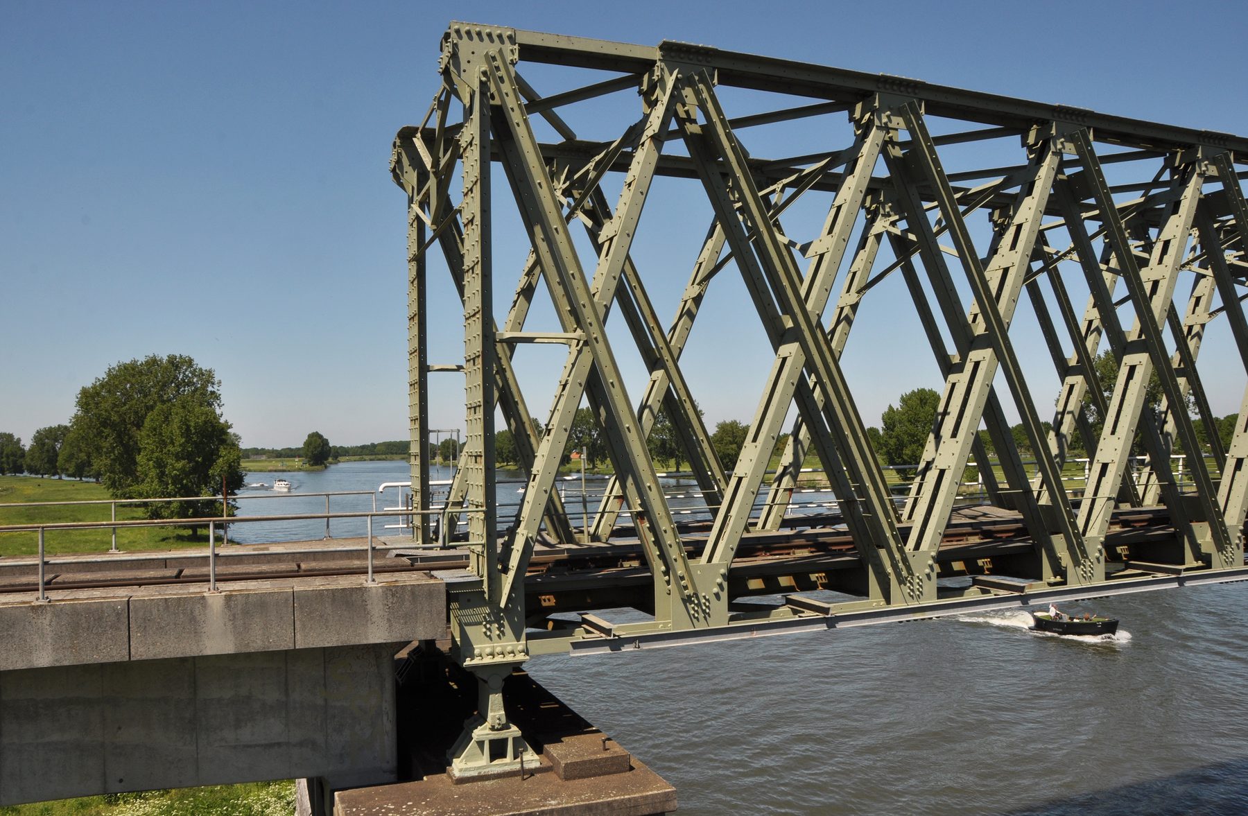 Spoorbrug en rivier gezien vanaf de route over Maasover